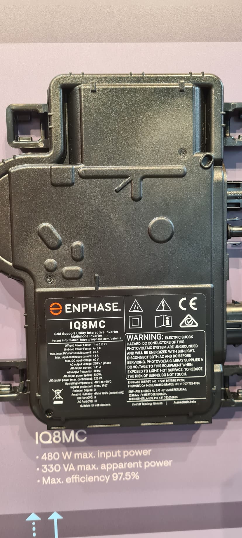 Närbild på en Enphase IQ8MC mikroväxelriktare med produktnamn och tekniska specifikationer synliga vid sidan av enheten.