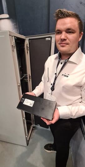 Pixii-representant håller upp en batterimodul vid mässmonter